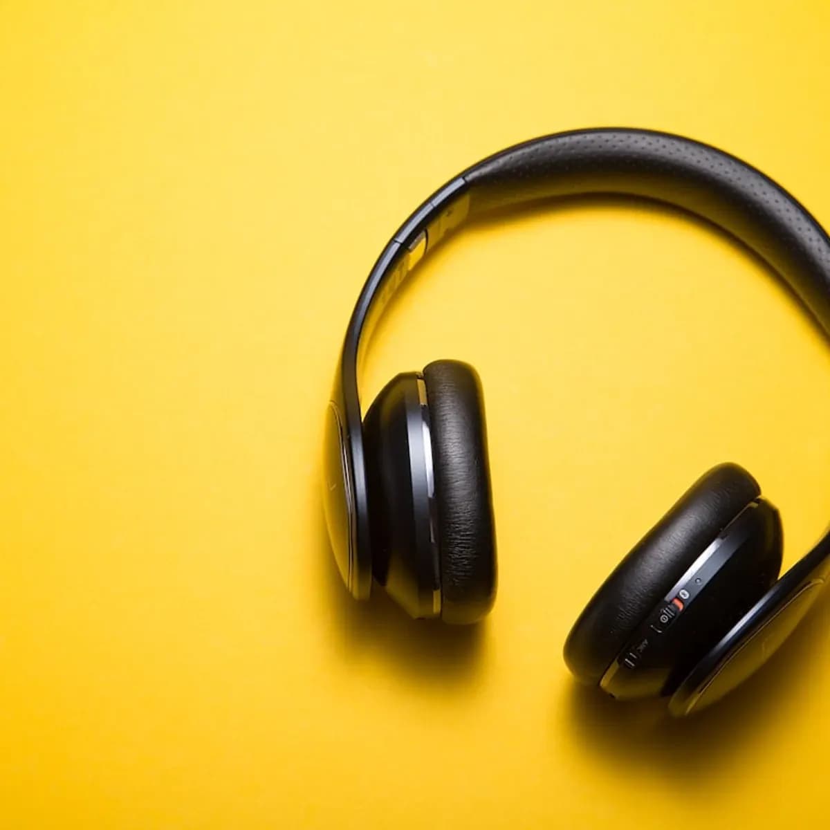 A pair of over-ear headphones beside a wireless earbud case